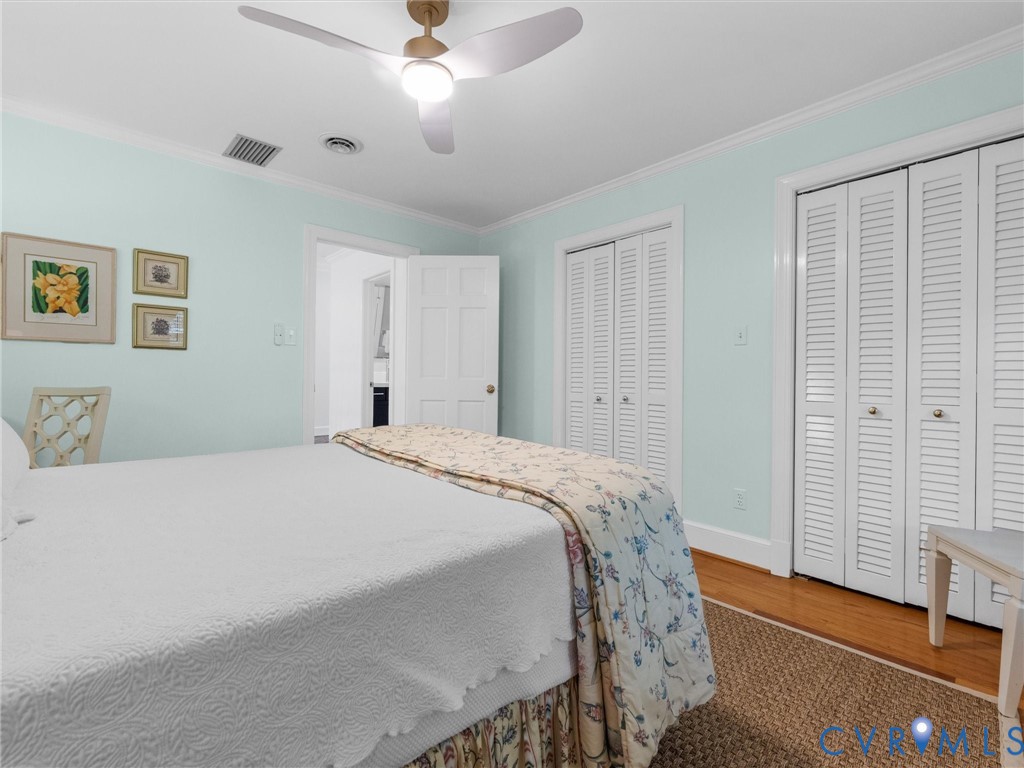 Integrated ceiling fan, crown molding, wood-finish flooring, and white louvered bifold closet doors