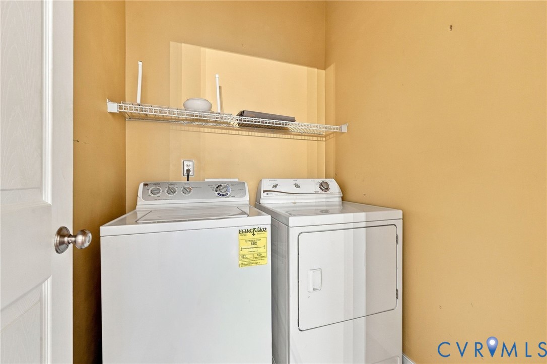 White top-loading washing machine and dryer with a wire shelf above