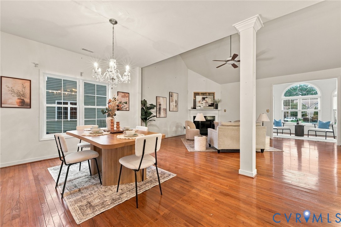 Open concept interior with wood-finish flooring, a decorative column, and a modern chandelier