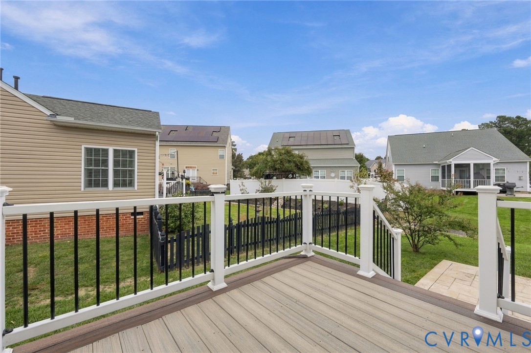 Composite deck with white railings and black balusters, featuring a grassy backyard