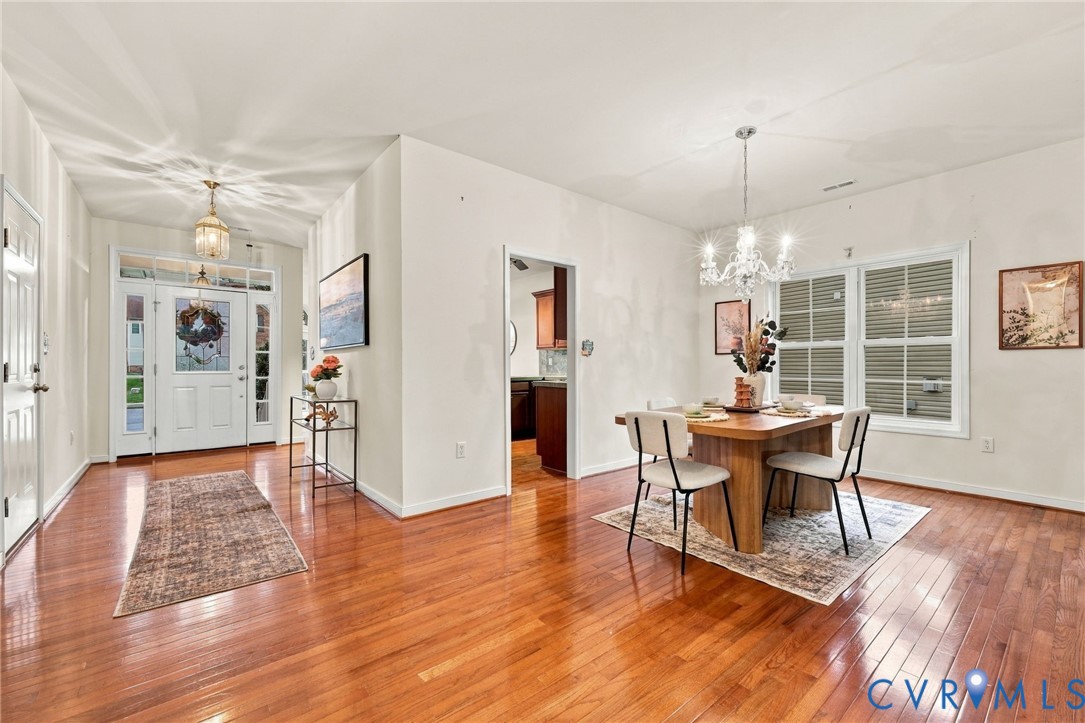Hardwood-finish flooring throughout, a front entry door with sidelights and transom window, and a chandelier-style ceiling fixture