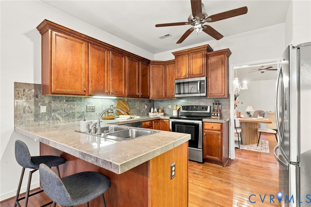 Kitchen featuring wood-finish cabinetry, stainless steel appliances, a double basin sink, and stone-finish countertops