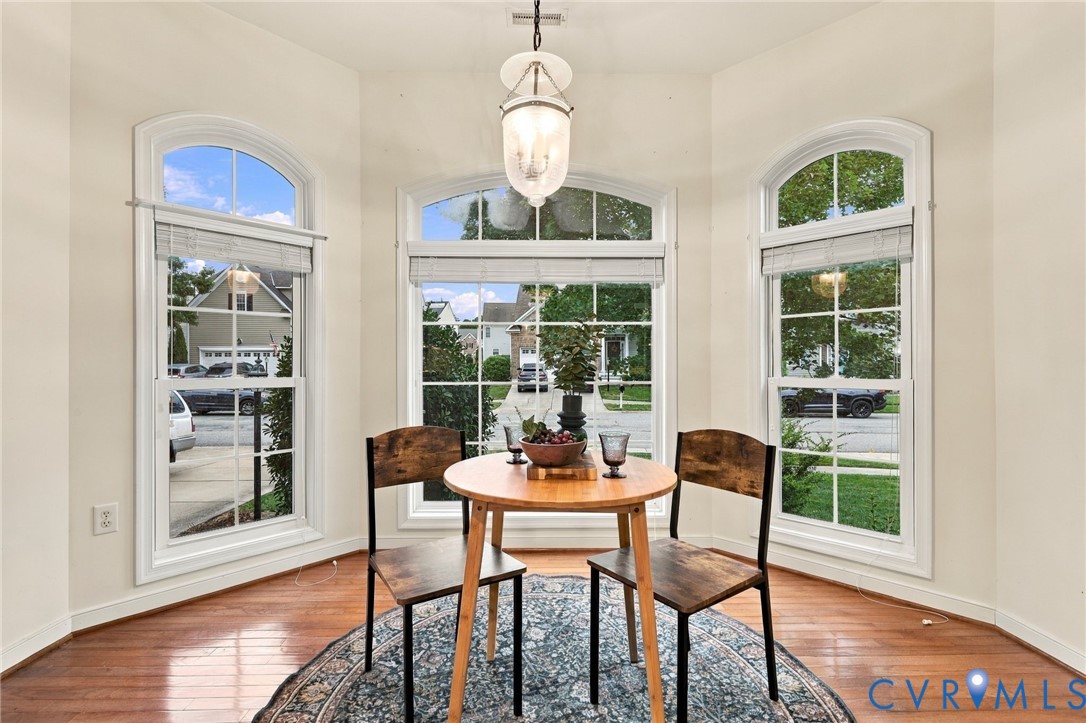 Bay window with three arched windows, wood-finish flooring, and a central pendant light fixture