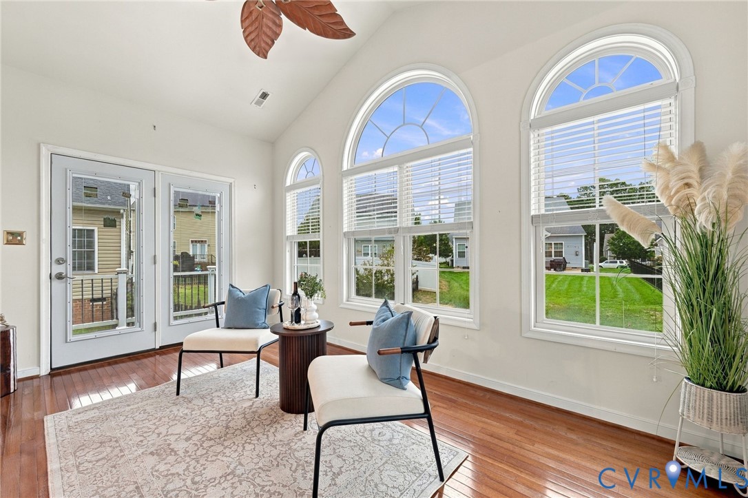 Vaulted ceiling, hardwood flooring, arched windows, double French doors, and a ceiling fan