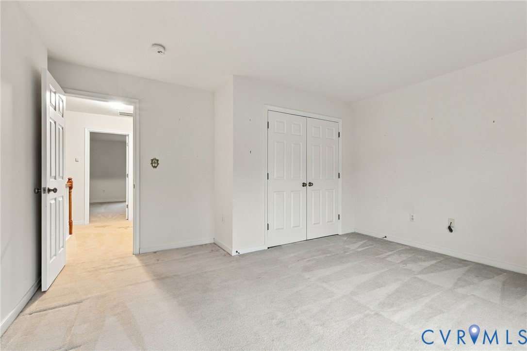 Carpeted room with a paneled bi-fold closet door and a six-panel door opening to an interior hallway