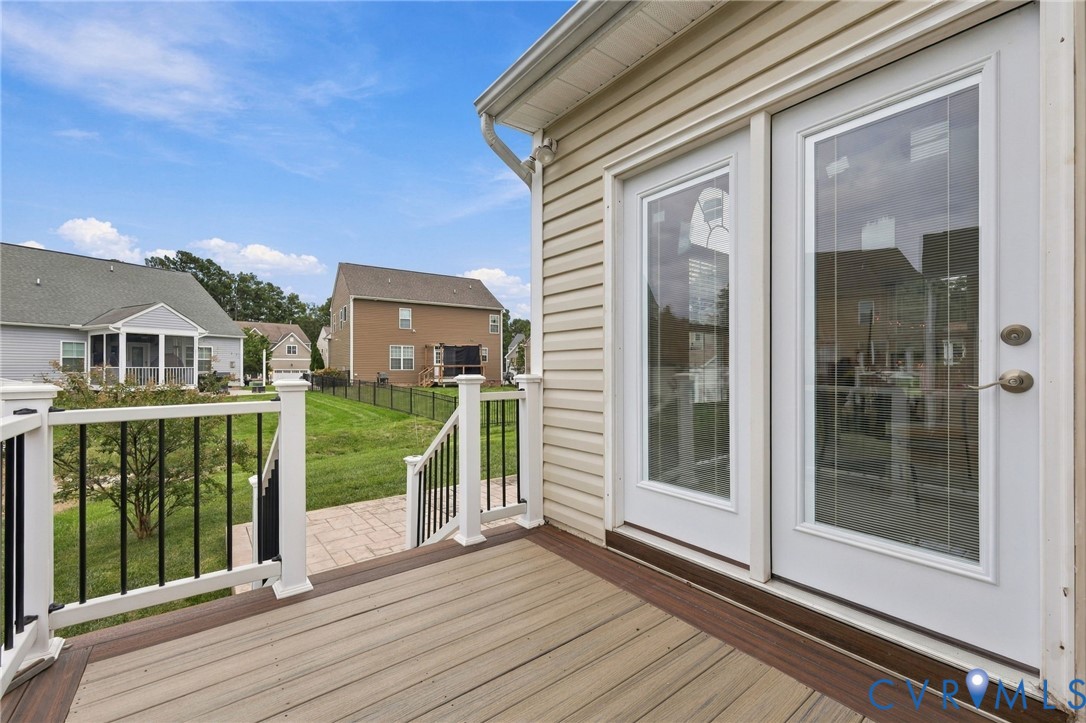 Exterior deck with composite decking, white railings with black balusters, and dual glass-panel doors