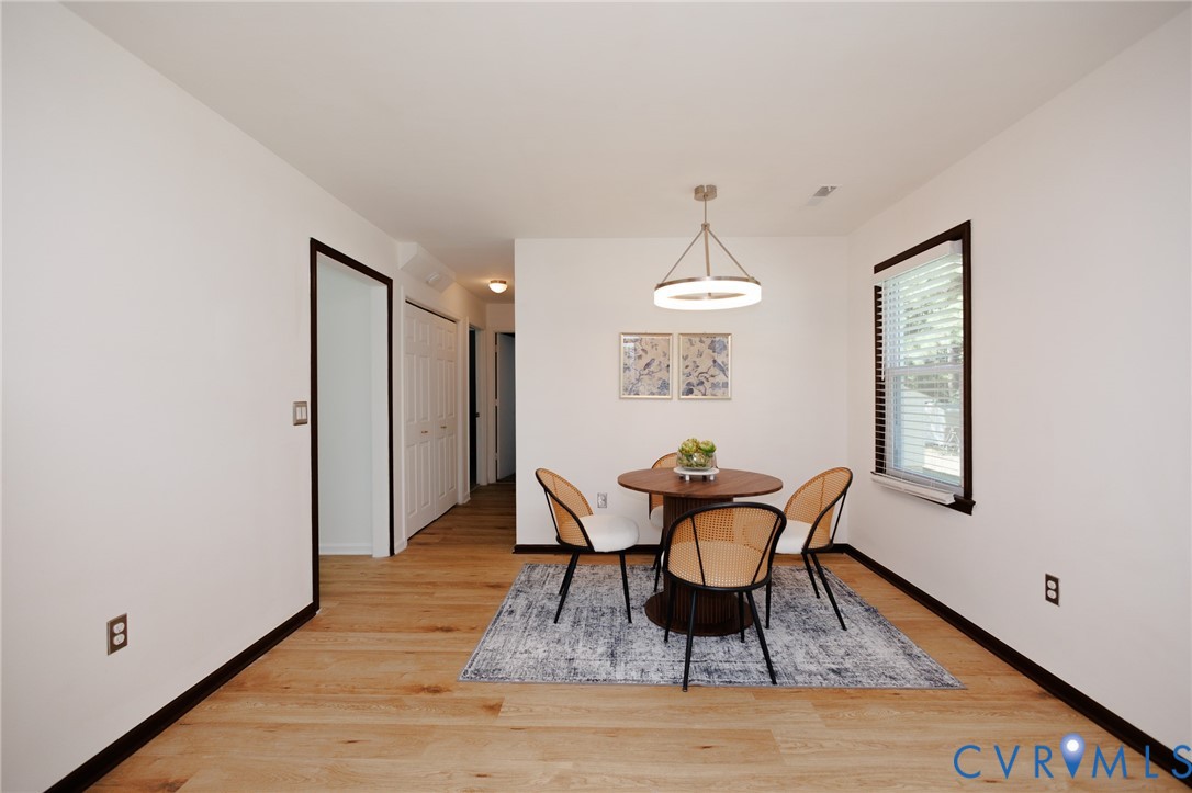 Wood-finish flooring throughout, bright white walls, and a contemporary chandelier