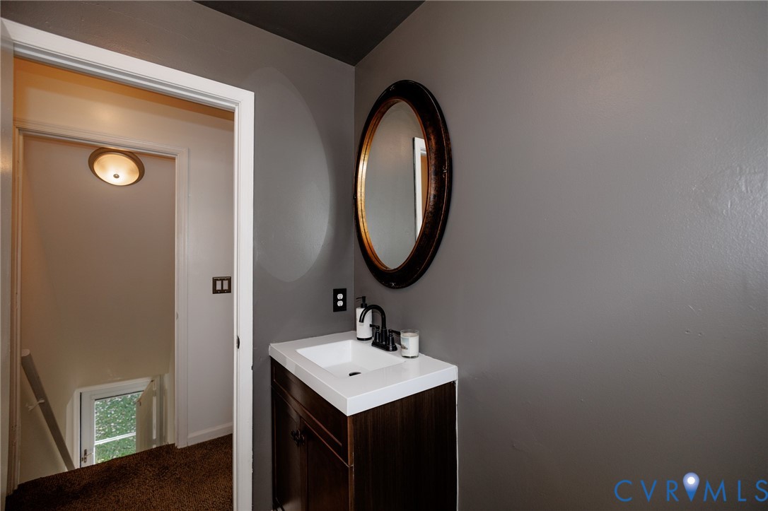 Modern vanity with an integrated white sink, dark wood-finish cabinetry, and a black faucet