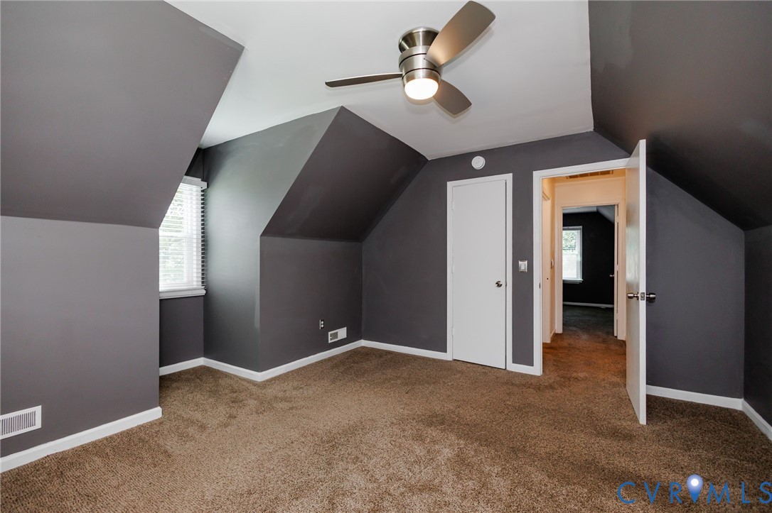 Sloped ceilings, wall-to-wall carpeting, white window blinds, white interior doors, and a ceiling fan with integrated lighting