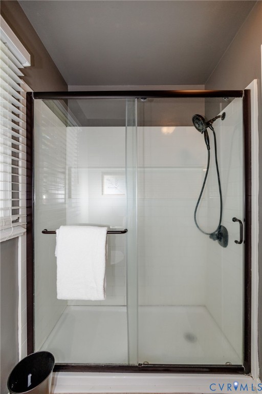 Glass-enclosed shower with dark bronze framing and a wall-mounted shower head