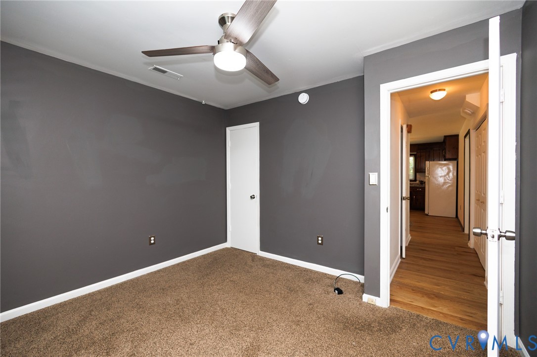 Carpeted room with a ceiling fan light fixture and a white door