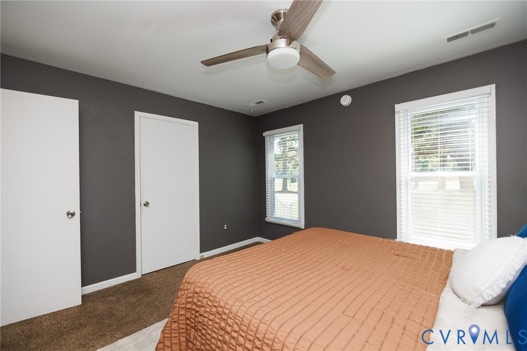 Warm-toned walls accentuating two white doors, two windows, and a ceiling fan with light fixture