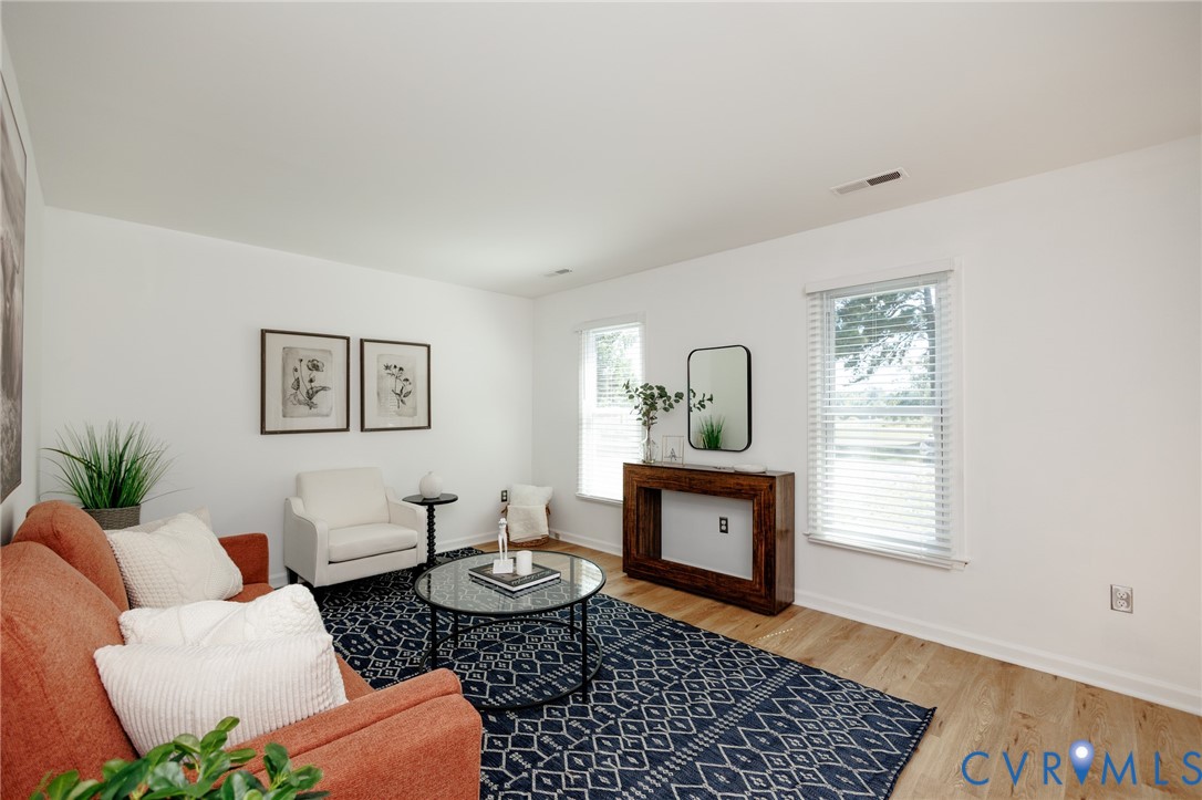 Light wood-finish flooring, white walls, and multiple windows with blinds