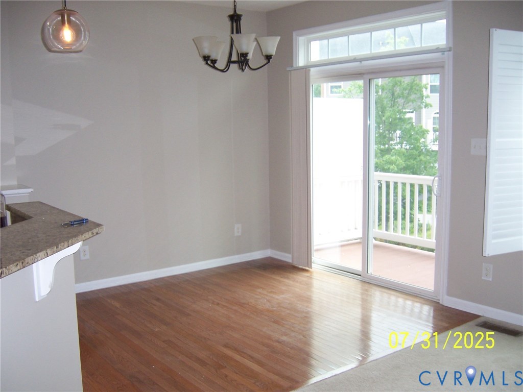 Unfurnished dining area with wood finished floors and a chandelier Unfurnished dining area with wood finished floors and a chandelier