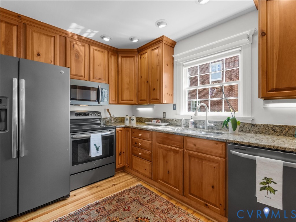 Kitchen featuring wood cabinetry, granite countertops, stainless steel appliances, and a double-basin sink with a gooseneck faucet