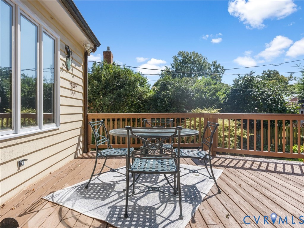 Exterior wood deck featuring a natural wood railing, horizontal siding, and multiple windows