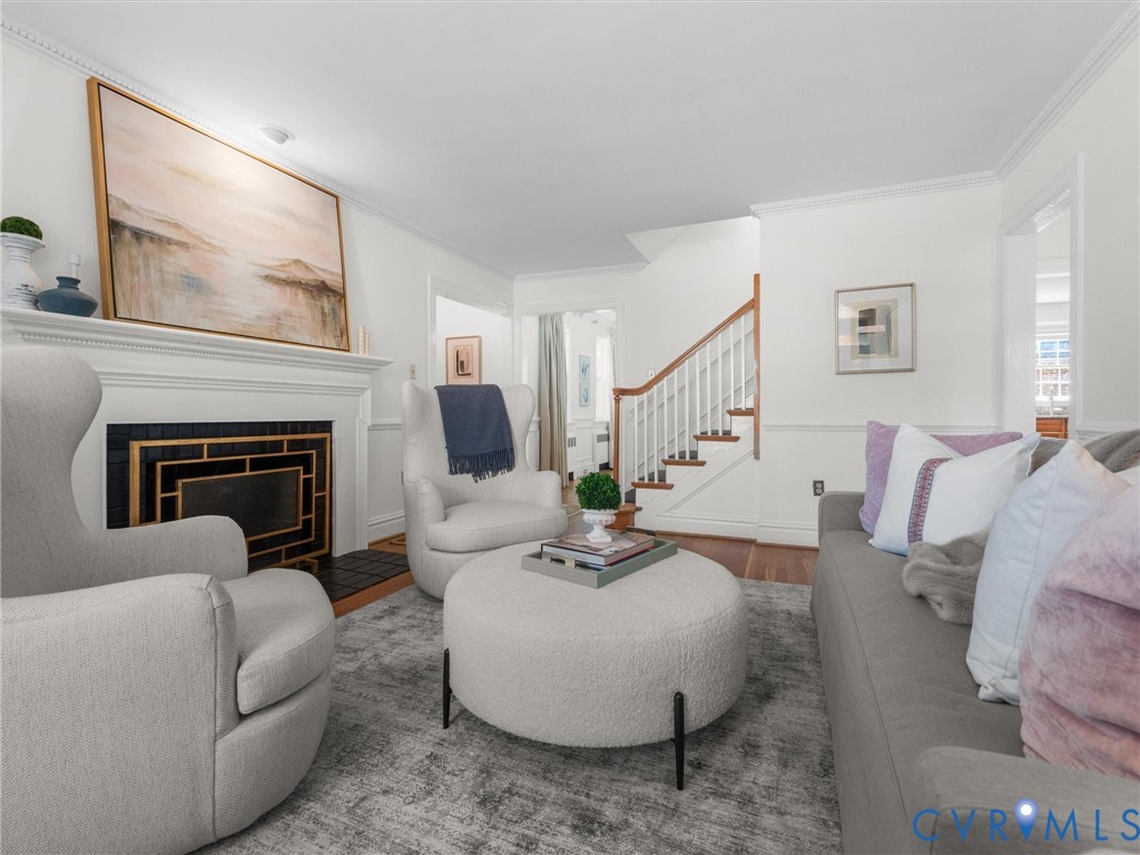 Living space featuring a fireplace with a decorative screen, a white mantel, and crown molding