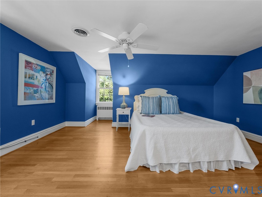 Hardwood flooring, sloped ceilings, a ceiling fan, and a single window