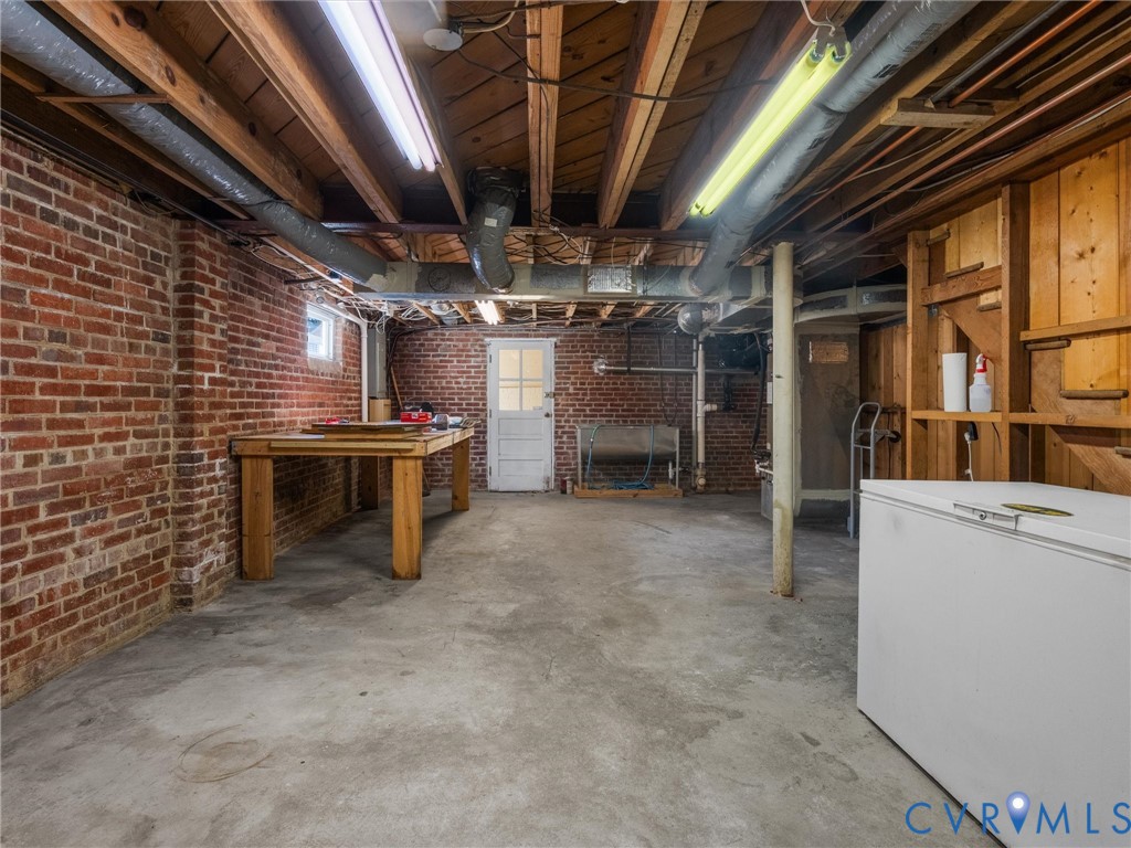 Exposed brick walls, concrete flooring, exposed ceiling joists, wood-paneled wall, and a utility sink