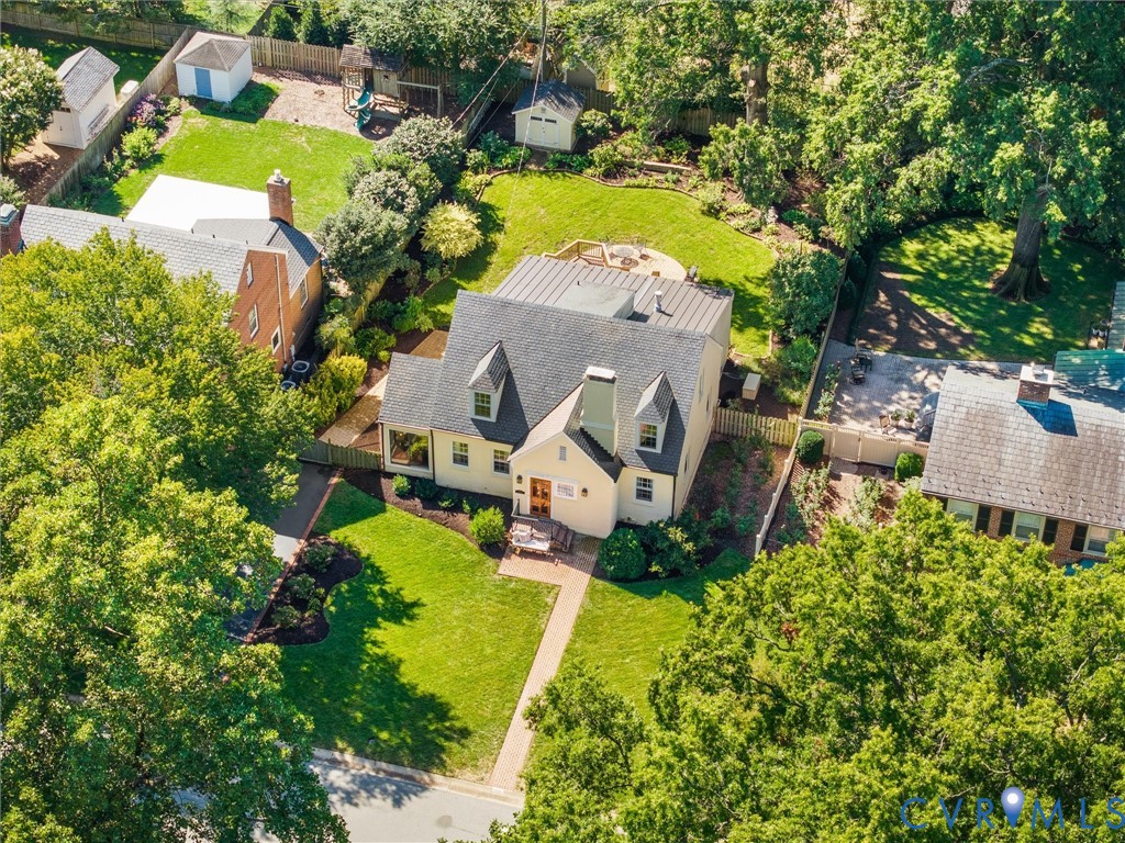 Dormered home with a gabled roof, spacious backyard, paved walkway, and mature landscaping