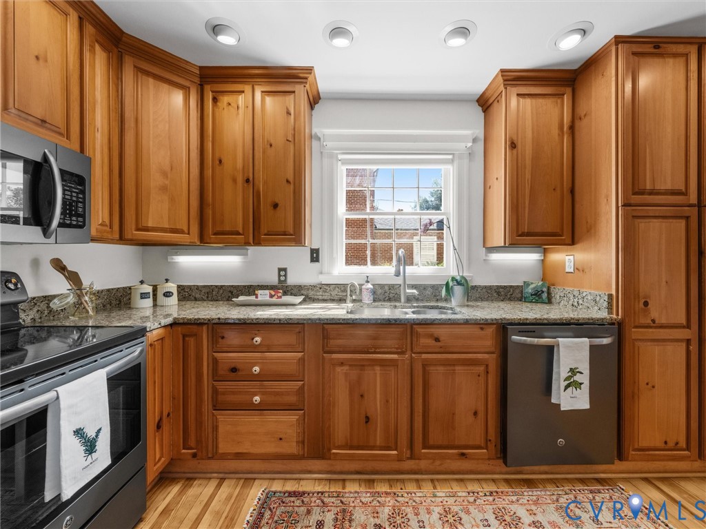 Kitchen with wood-finish cabinetry, stainless steel appliances, granite countertops, and recessed lighting