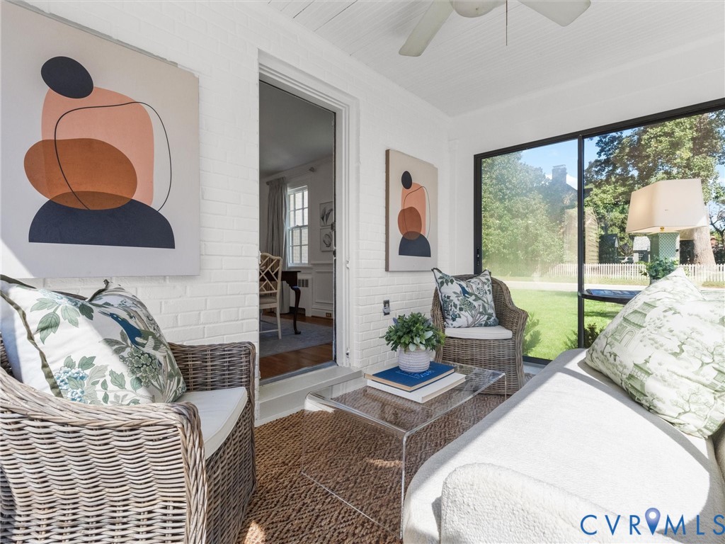 Sunroom featuring white painted brick walls, exposed beam ceiling, and a ceiling fan