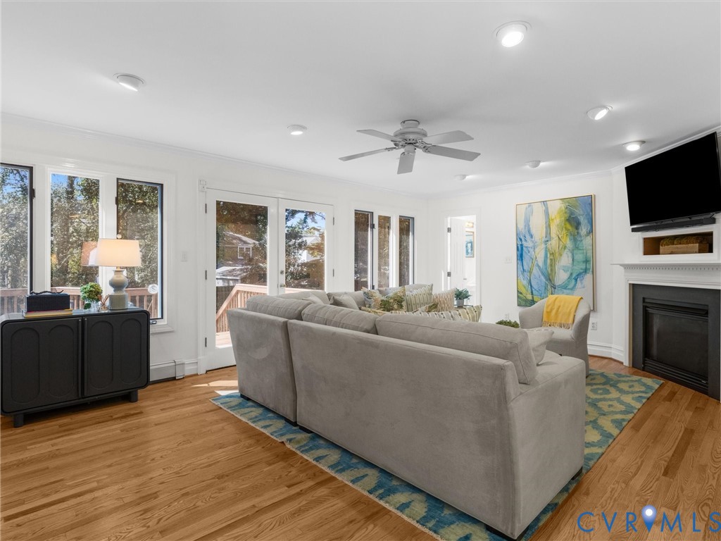 Hardwood flooring throughout, recessed lighting, ceiling fan, multiple glass doors, and a fireplace with a mantel