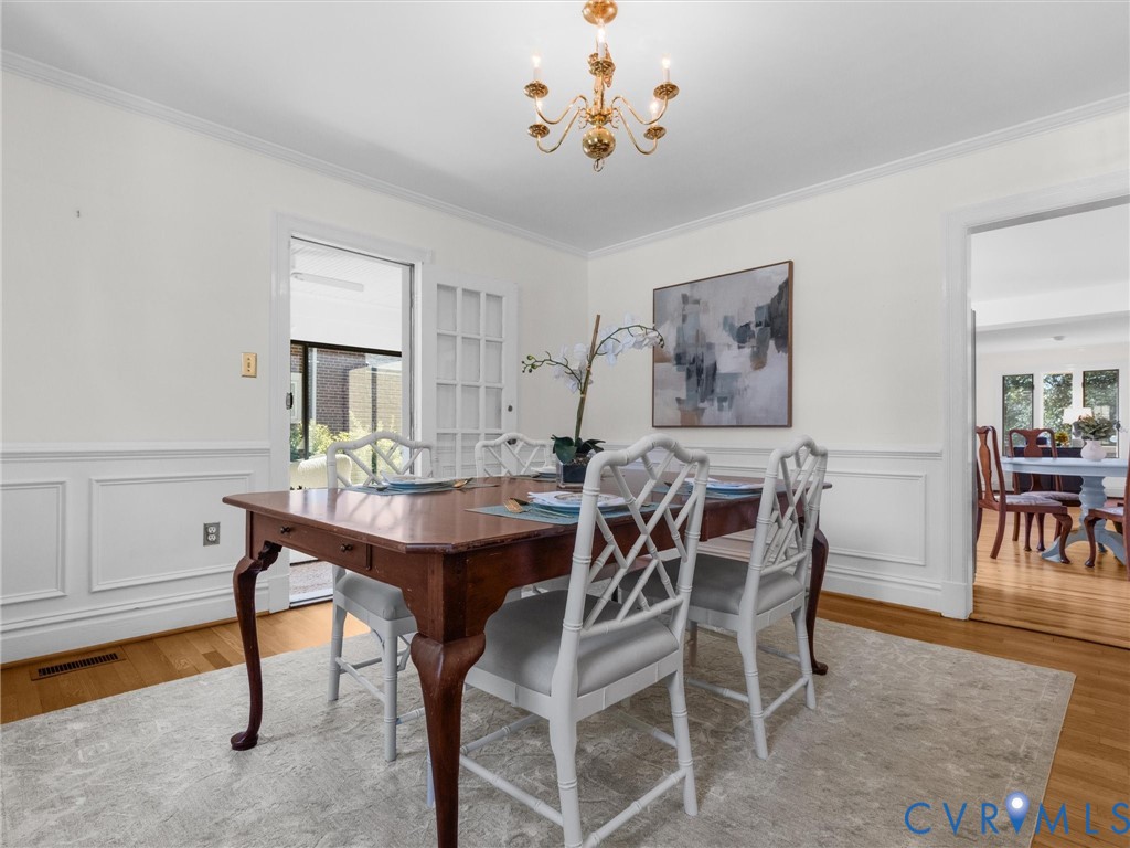 Hardwood flooring, crown molding, wainscoting, chandelier lighting, and a French door