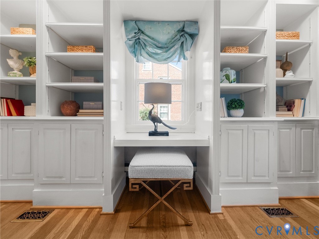 Built-in shelving with lower cabinetry, integrated desk space, and wood-finish flooring