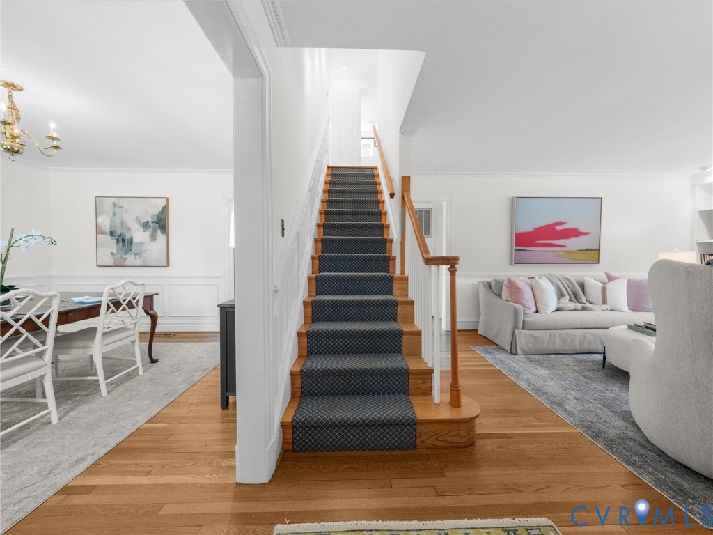 Hardwood flooring, wainscoting, and a staircase with a patterned runner