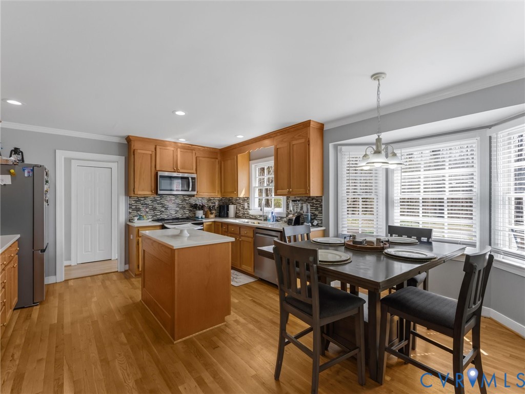 Wood-finish flooring, recessed lighting, wood cabinetry, stainless steel appliances, and a bay window with blinds