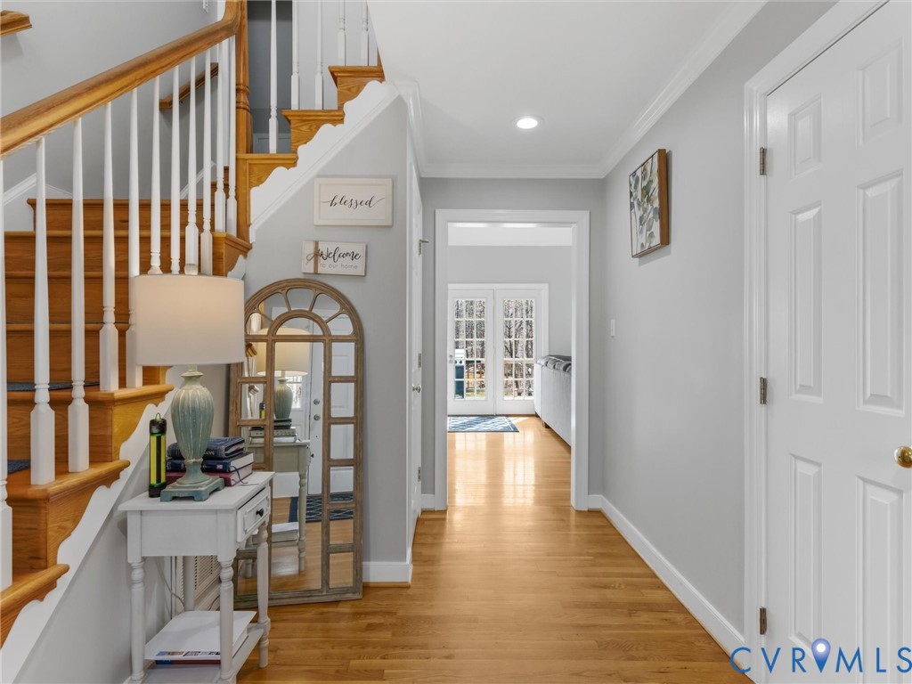 Hardwood flooring, painted white interior doors, crown molding, a staircase with white spindles, and recessed lighting Hardwood flooring, painted white interior doors, crown molding, a staircase with white spindles, and recessed lighting