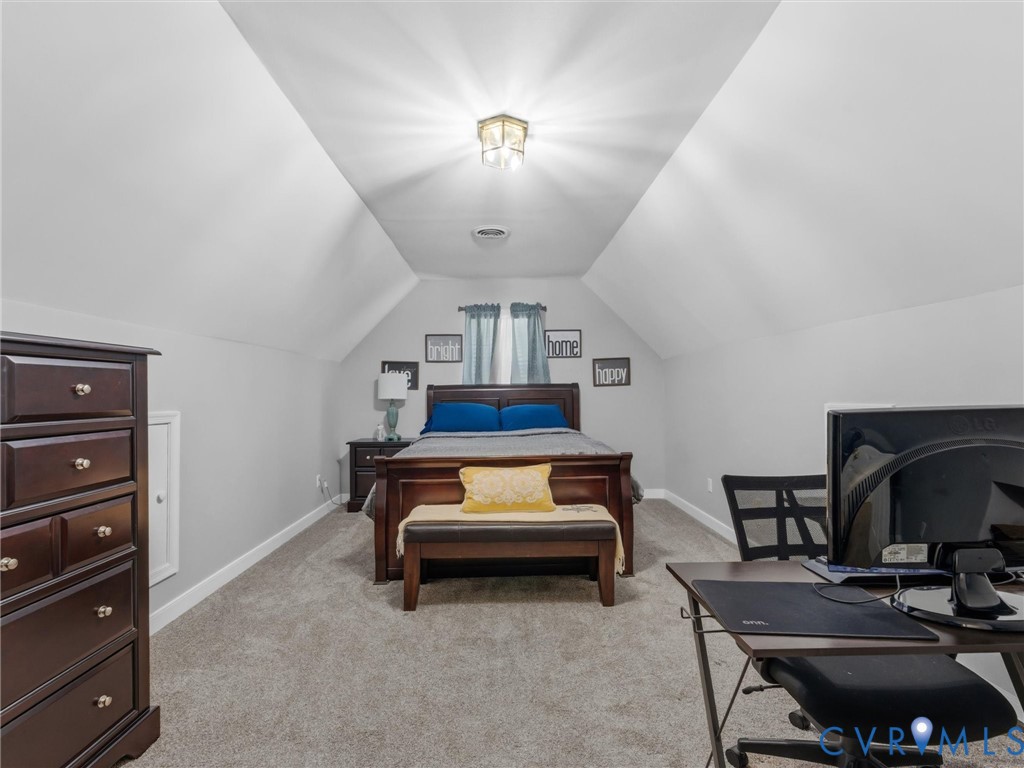 Vaulted ceiling with central lighting fixture and gray carpeted flooring