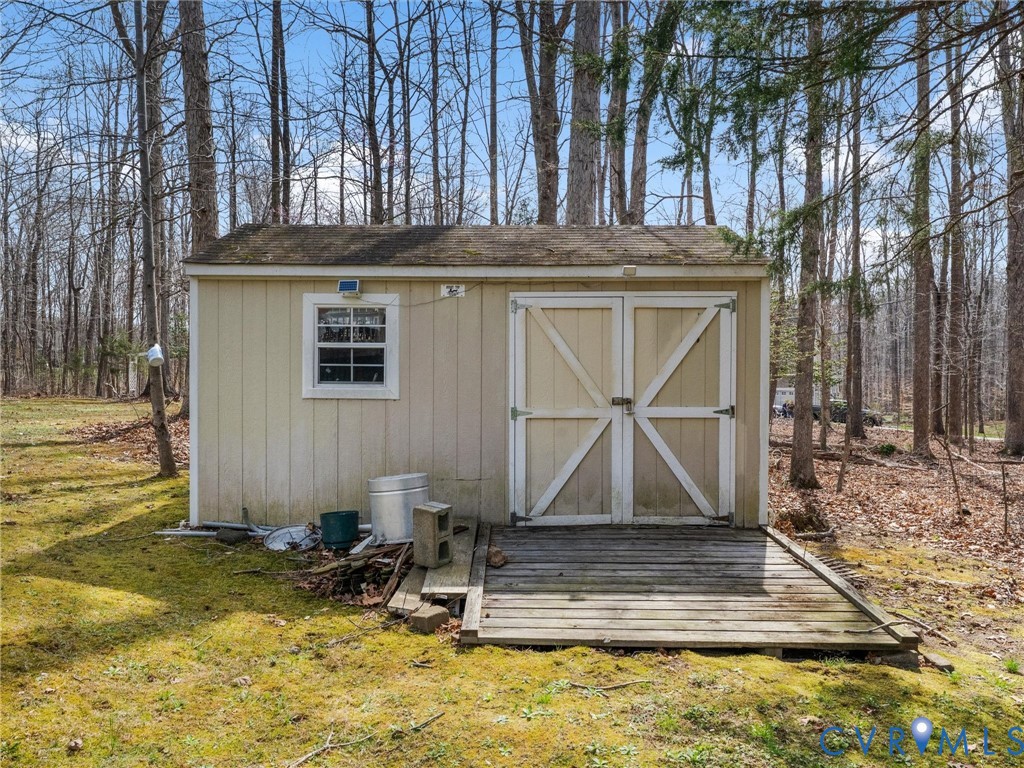 Detached storage shed with double doors, a single window, and a wood-plank ramp