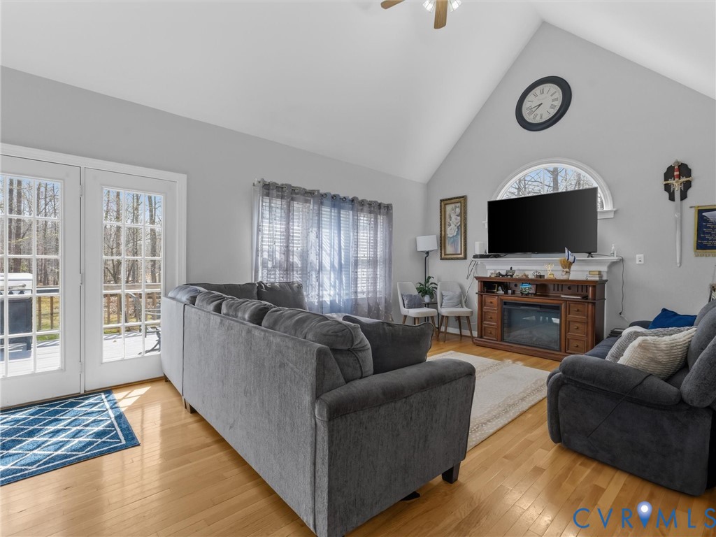 Vaulted ceiling with ceiling fan, wood-finish flooring, and French doors