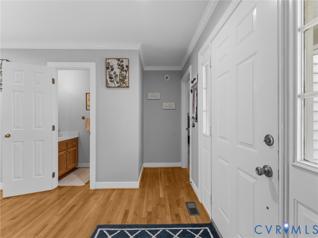 Hardwood flooring, painted interior doors, crown molding, and a bathroom vanity with wood-finish cabinetry Hardwood flooring, painted interior doors, crown molding, and a bathroom vanity with wood-finish cabinetry