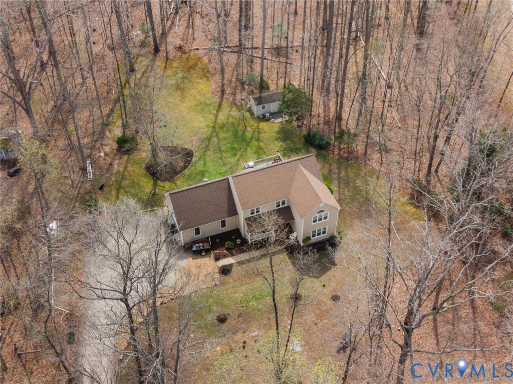 Expansive wooded property featuring a two-story residence with a brown shingle roof, a detached shed, and a circular driveway