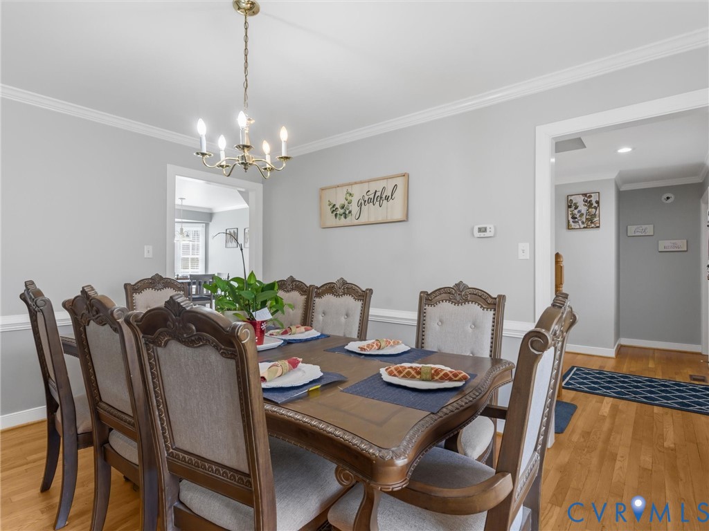 Hardwood flooring, crown molding, chair rail molding, and a brass-finish chandelier