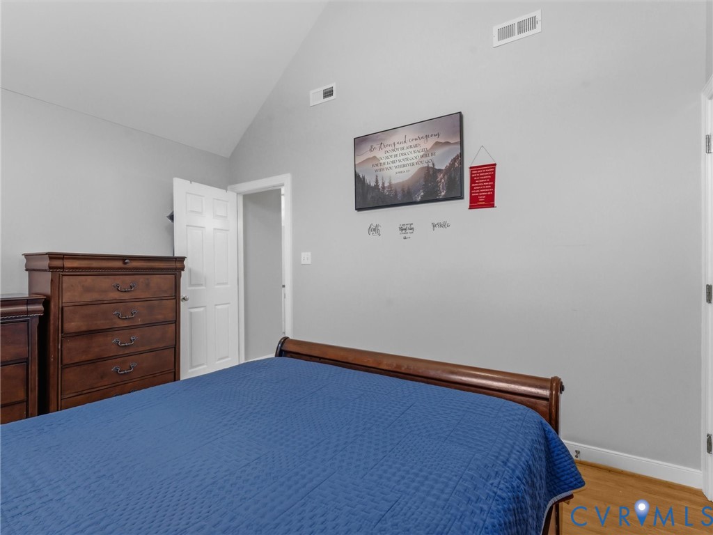 Vaulted ceiling, light gray wall paint, white trim, wood-finish flooring, white paneled door