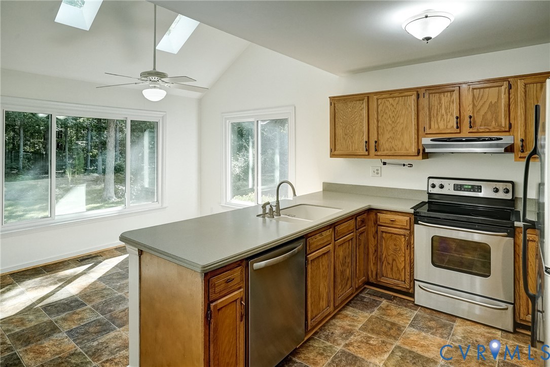 Sunny Kitchen featuring wood-finish cabinetry, stainless steel appliances, and a double basin sink.  Also freshly painted