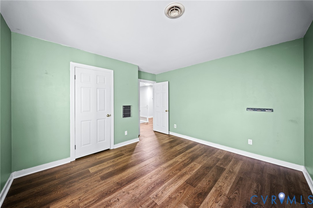 Interior room featuring wood-finish flooring, white six-panel doors, and an integrated wall-mounted media bracket
