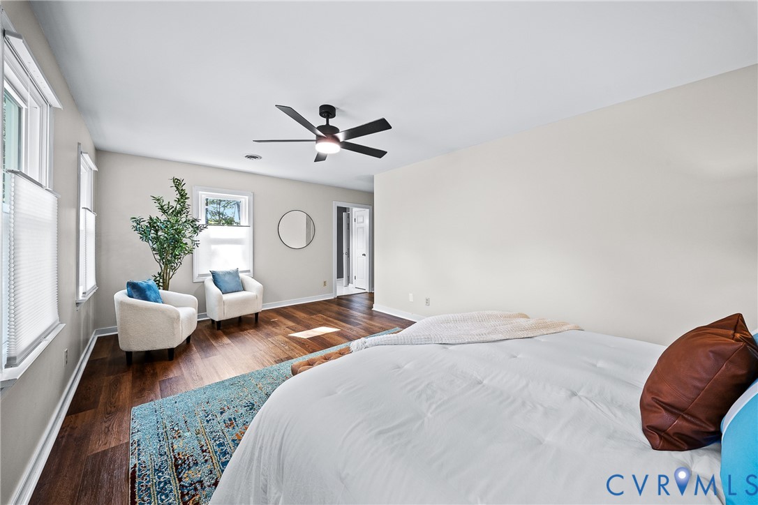 Room featuring wood-finish flooring, a matte black ceiling fan with an integrated light fixture, and multiple windows