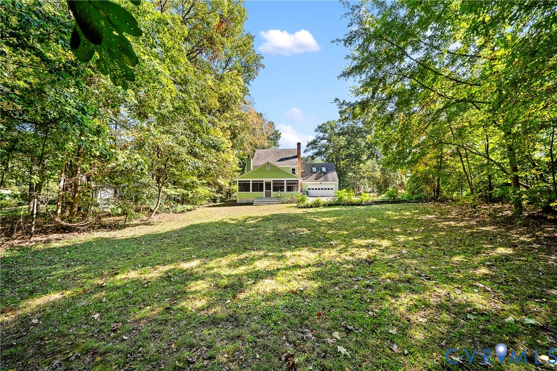 Expansive lot featuring mature trees, a screened-in porch, attached garage, and a wood-sided exterior Expansive lot featuring mature trees, a screened-in porch, attached garage, and a wood-sided exterior