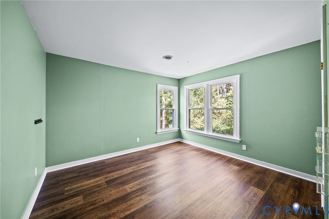 Room featuring wood-finish flooring, crisp white trim, and oversized double-hung windows