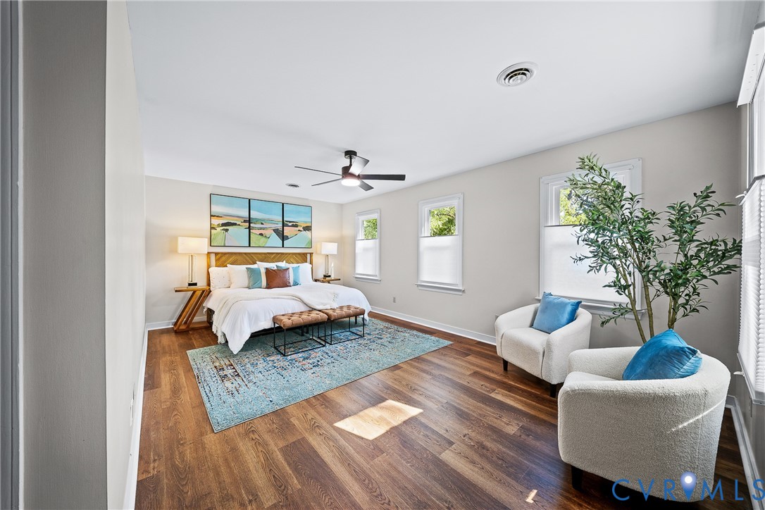 Room featuring wood-finish flooring, three windows with custom cellular shades, and a ceiling-mounted fan with integrated lighting