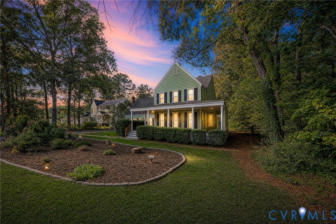 Traditional exterior featuring horizontal lap siding, covered front porch with columns, multi-pane windows with shutters, and mature wooded surroundings
