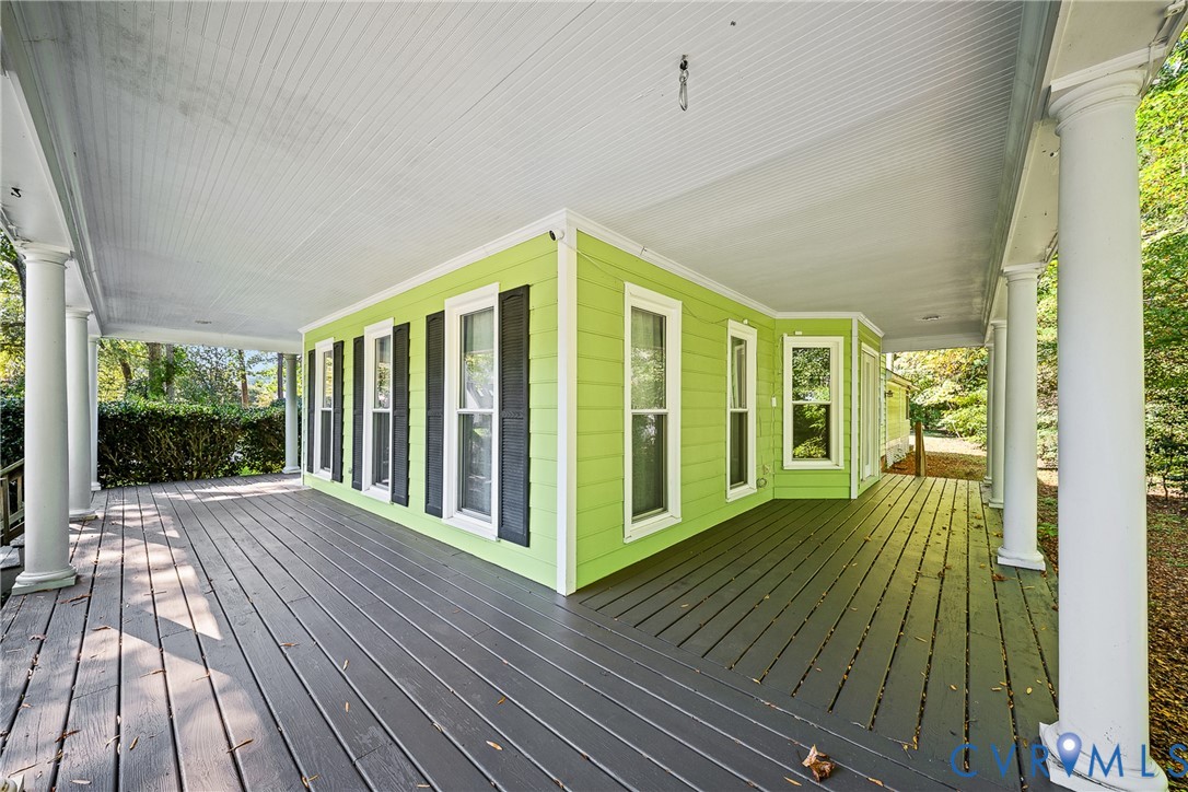 Wraparound covered porch featuring painted wood decking, structural columns, horizontal lap siding, and window shutters Wraparound covered porch featuring painted wood decking, structural columns, horizontal lap siding, and window shutters