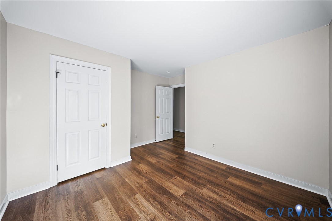 Room featuring wood-finish flooring, neutral wall paint, and two six-panel interior doors