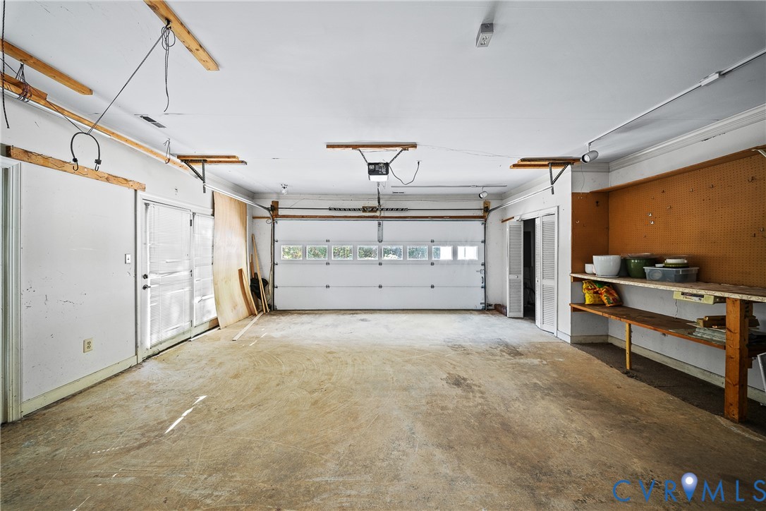 Two-car garage featuring a sectional door with windows, built-in wooden shelving, pegboard wall organization, and a private side-entry door