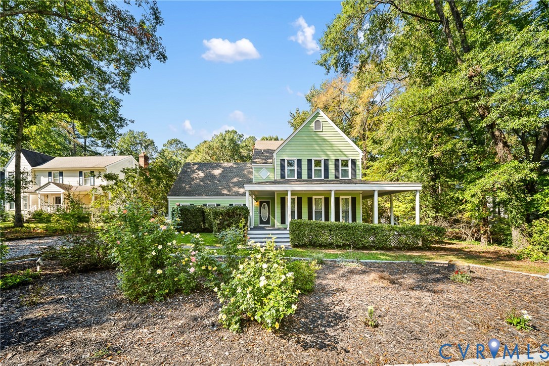Traditional two-story exterior featuring light-colored horizontal siding, a covered front porch, dark-toned shutters, and professional landscaping Traditional two-story exterior featuring light-colored horizontal siding, a covered front porch, dark-toned shutters, and professional landscaping
